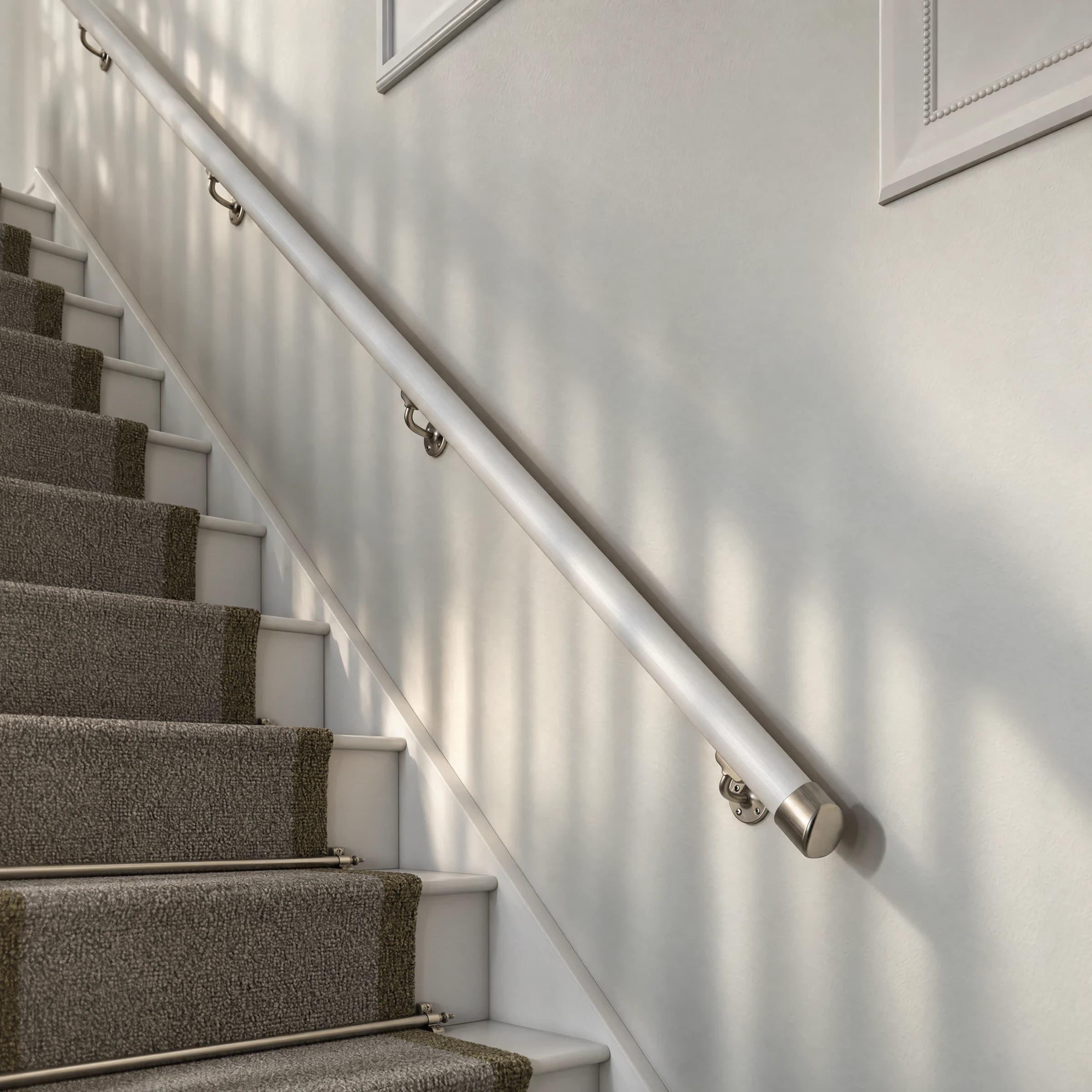 Brushed nickel wall handrail above stairs with a grey runner and white decorative mouldings